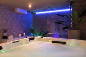 Une salle de spa avec un jacuzzi, un mur en briques et une plante en pot.