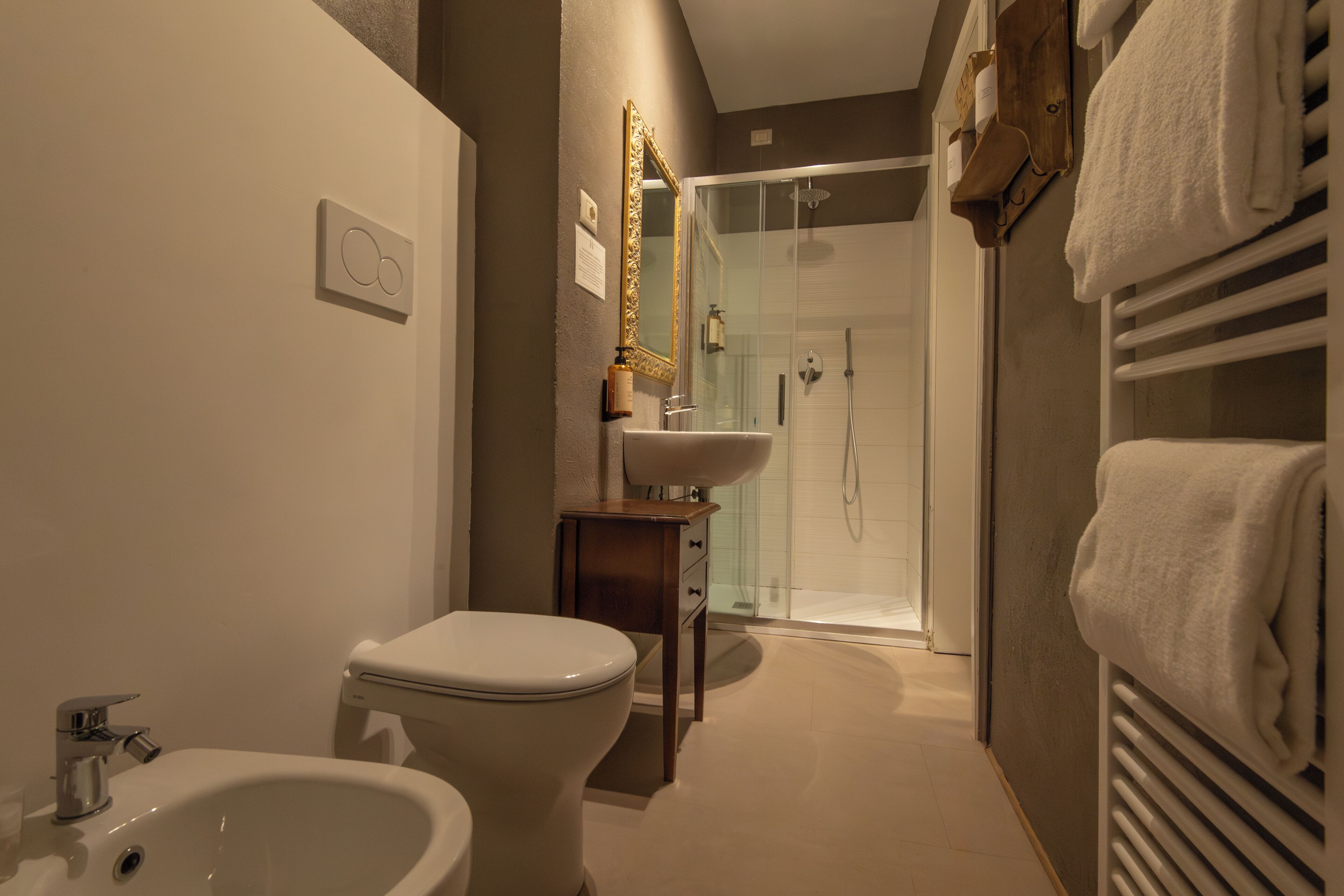 A bathroom with a toilet, bidet, sink, and glass-enclosed shower.