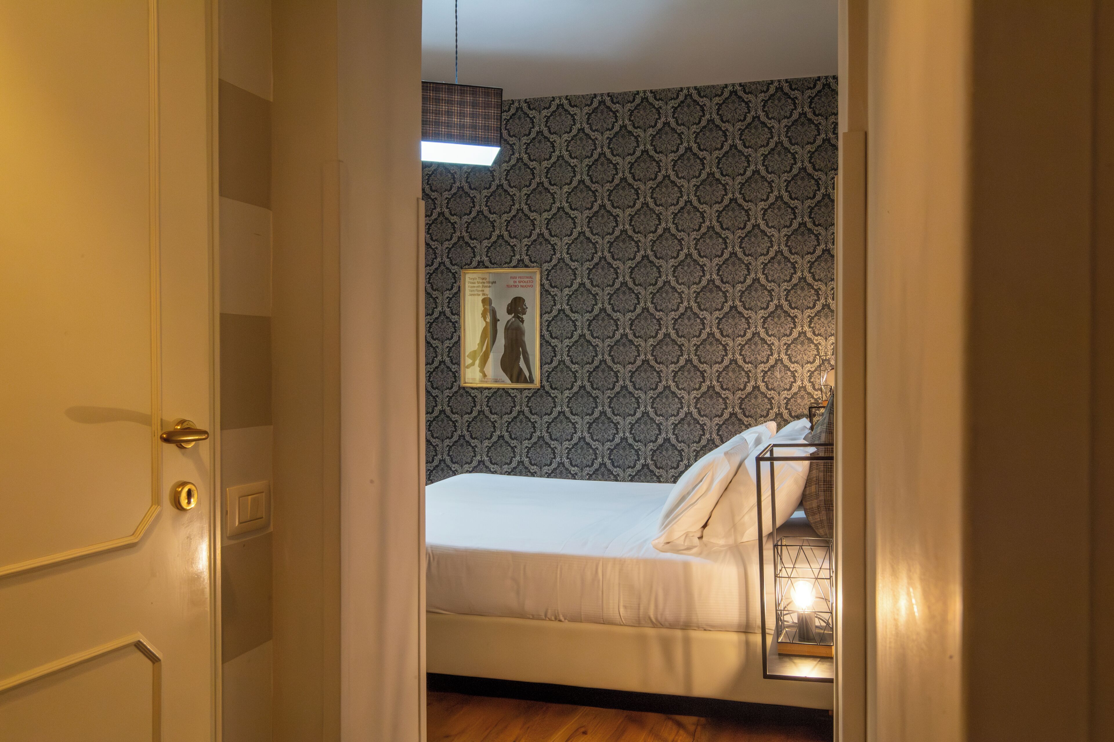 Ein Schlafzimmer mit einem Bett, einem Wandbild und einer Nachttischlampe.