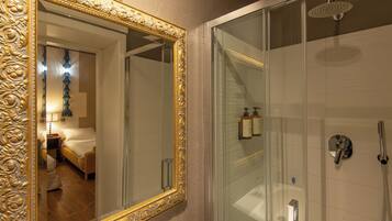 A bathroom with a glass shower enclosure, a gold-framed mirror, and a visible bathroom sink.