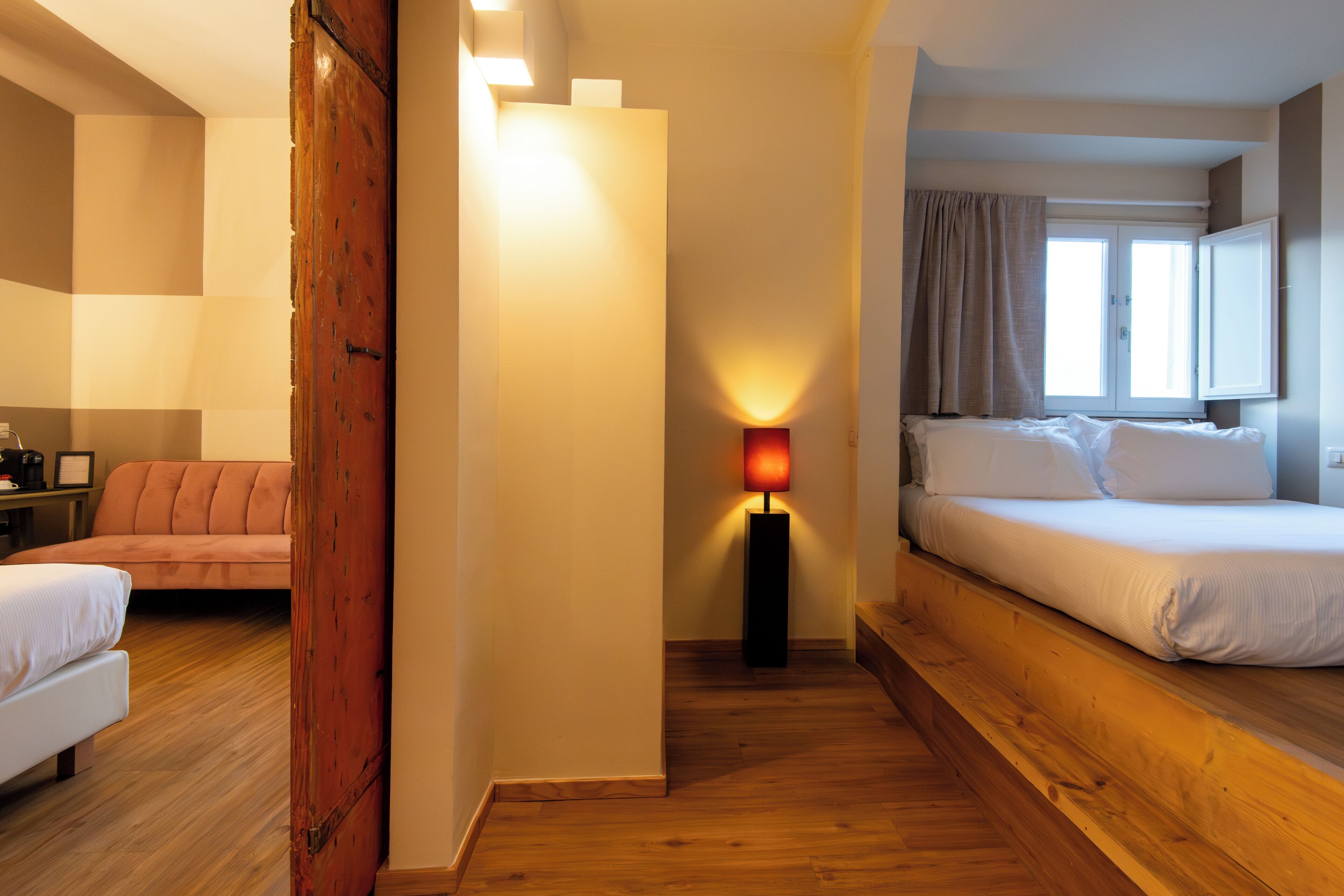Una habitación de hotel con cama, sofá, escritorio y lámpara.