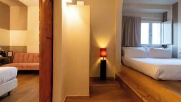 A hotel room with a bed, a sofa, a desk, and a lamp.