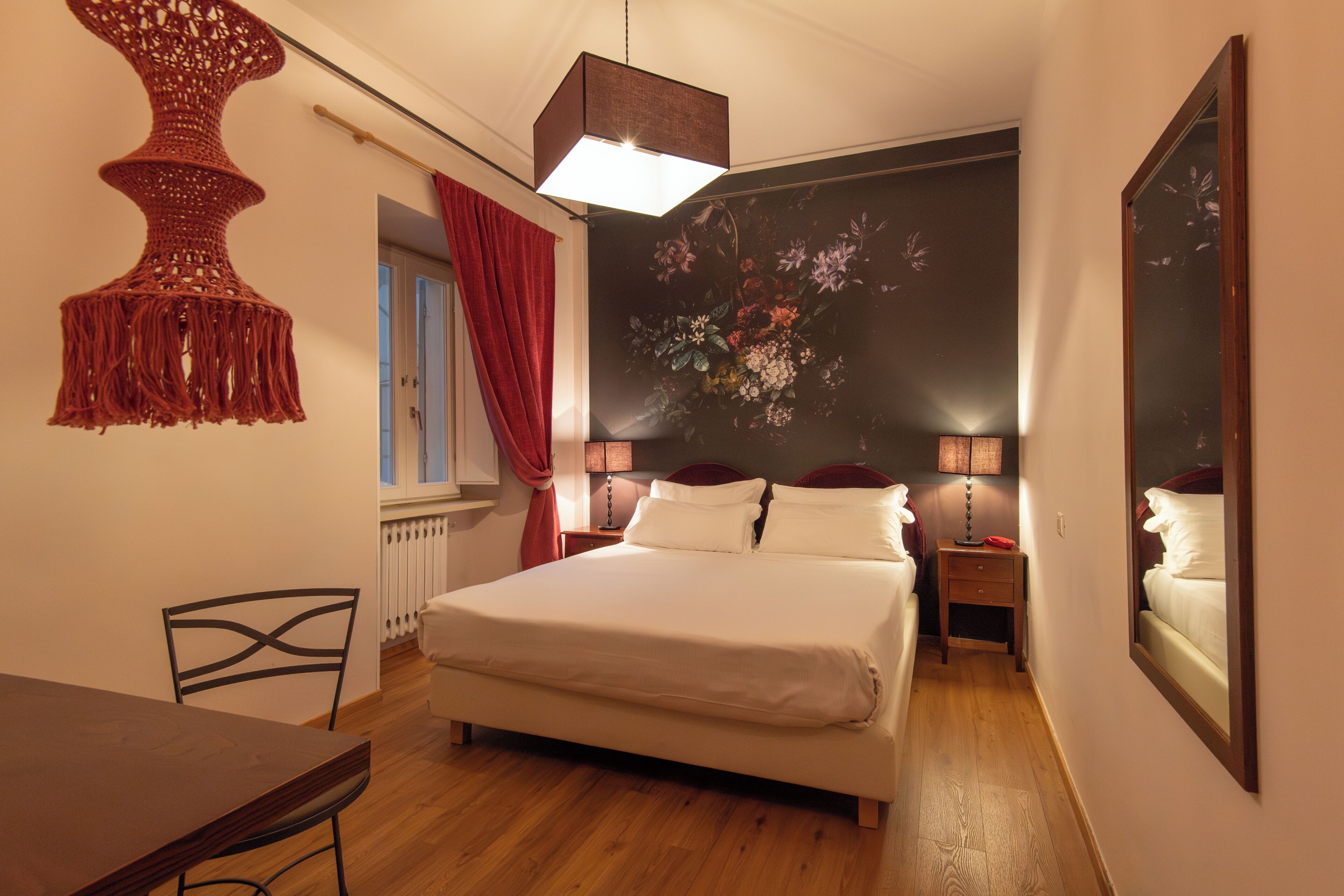A bedroom with a bed, bedside tables, a hanging light fixture, and a large mirror.