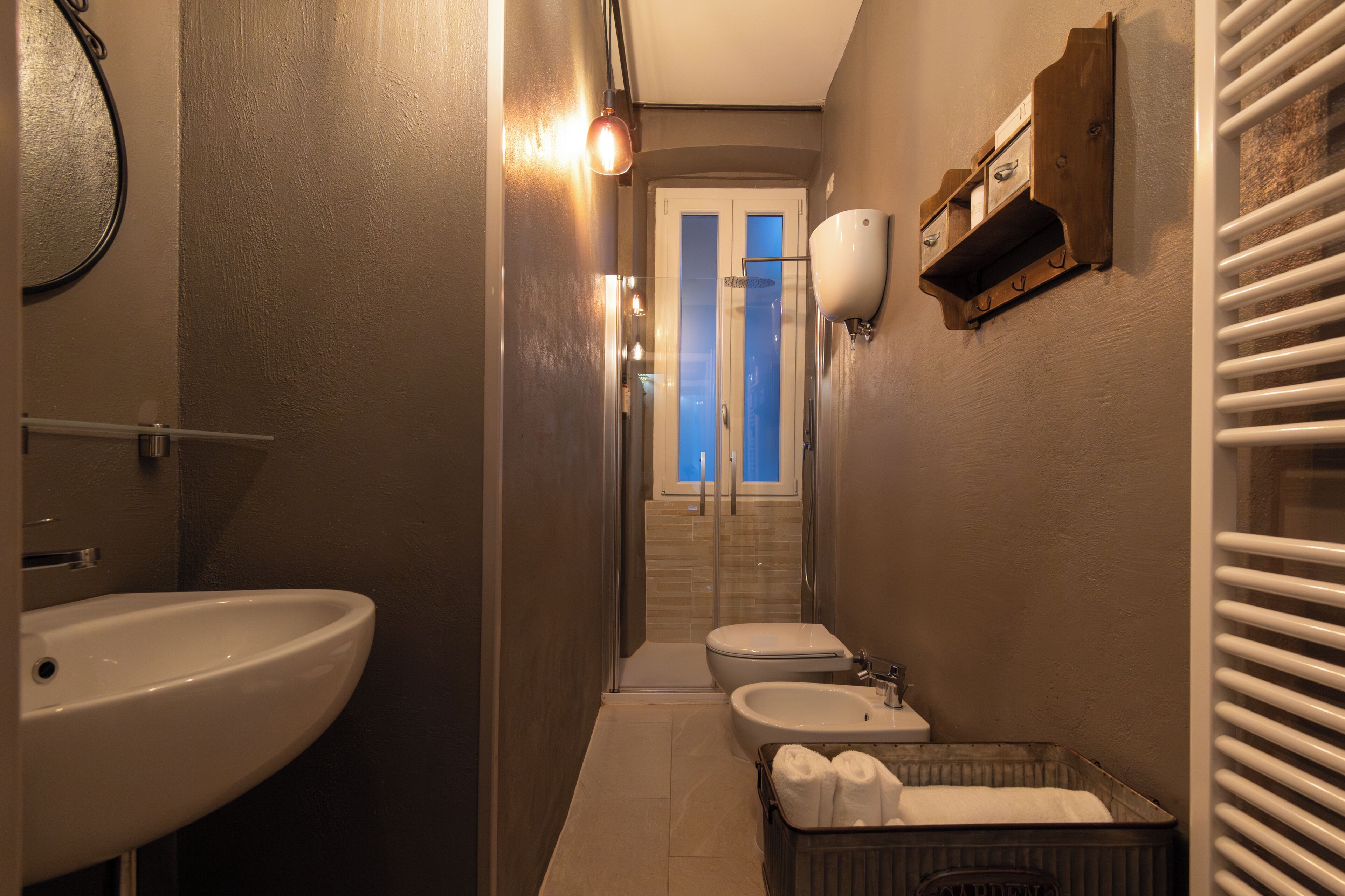 Un baño pequeño con lavamanos, inodoro, bidé, toallero y zona de ducha.