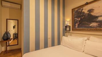 A hotel room with a bed, a large painting, a mirror, and a lamp.
