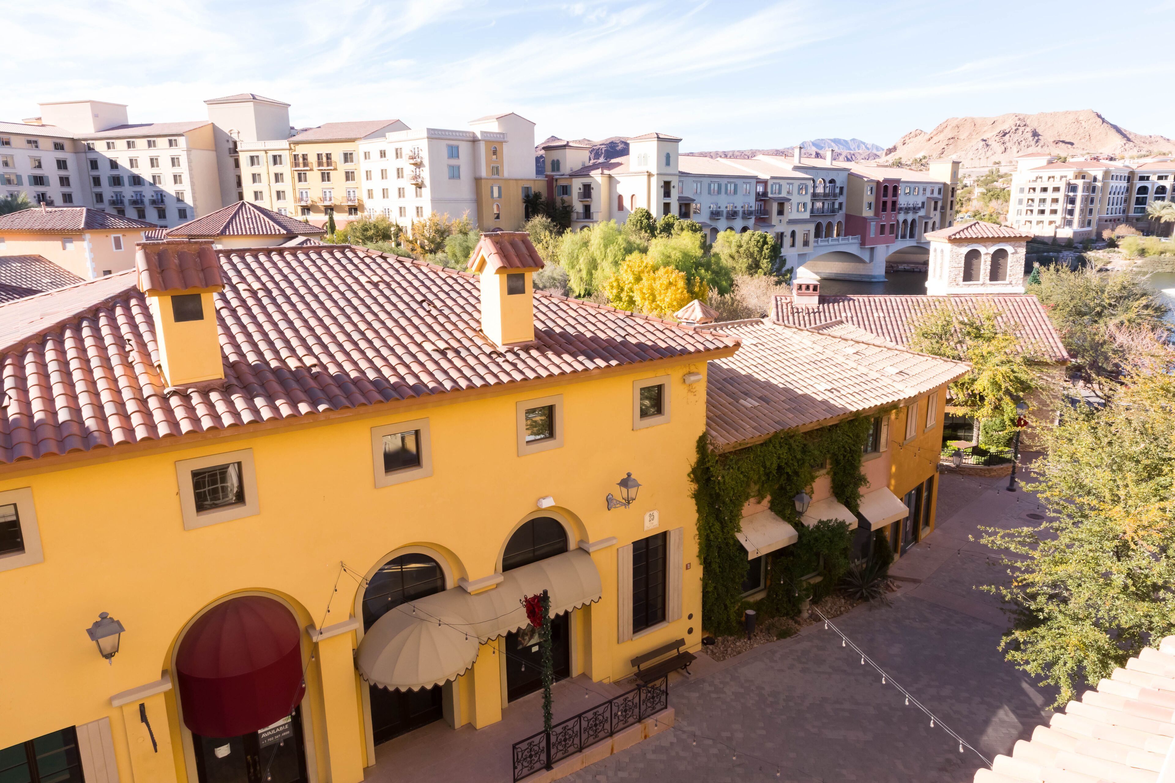 Un edificio giallo con tetto in tegole, finestre ad arco e tenda da sole rossa.