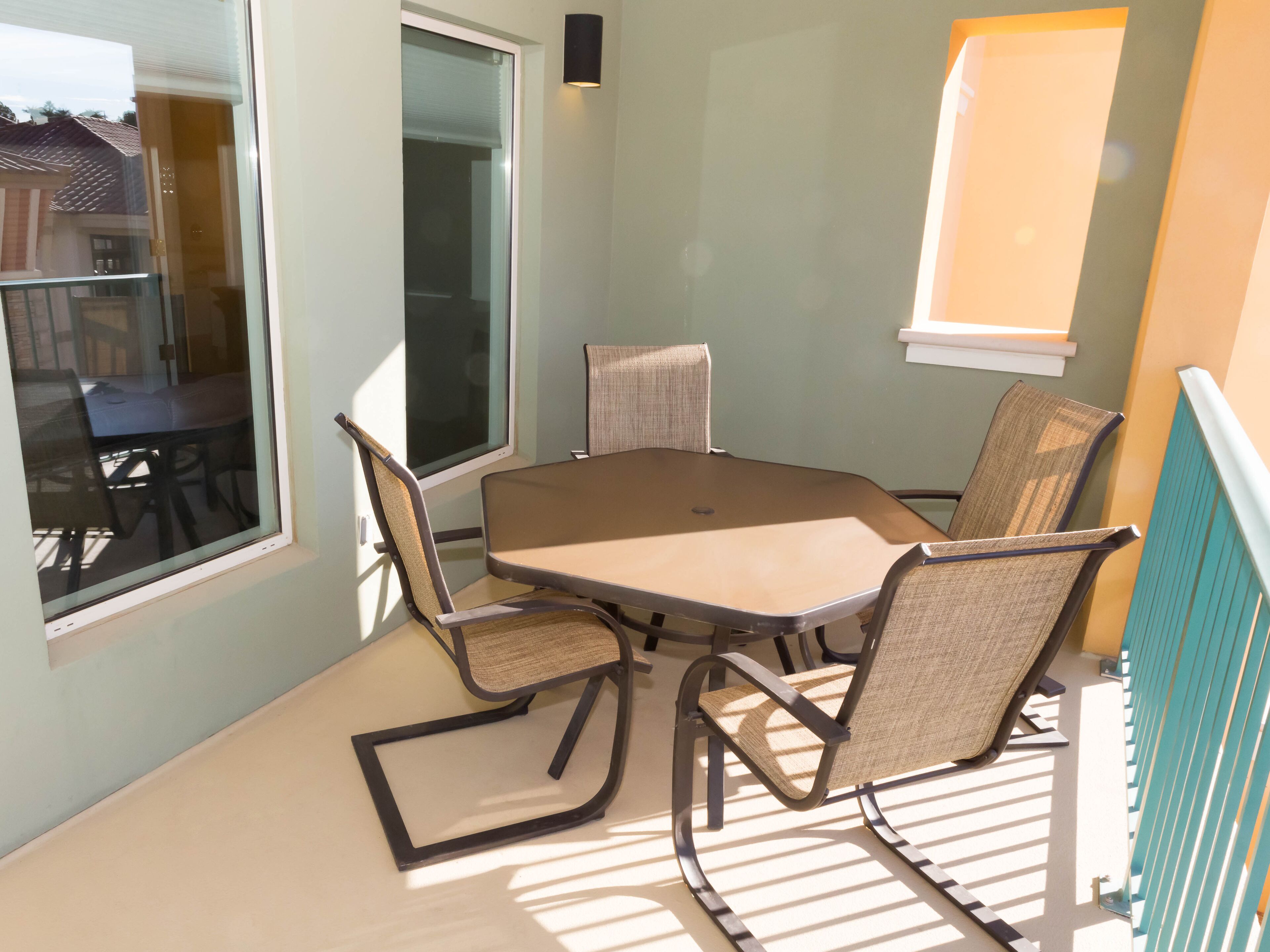A dining area with a table and four chairs, a window, and a wall-mounted light fixture.