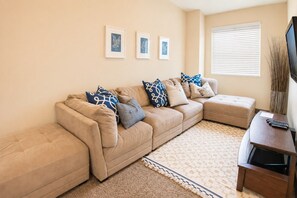 A living room with a beige sectional sofa, a patterned rug, and framed artwork on the wall. - Two heated pools/spas, pond, backyard w/ BBQ (Washington)
