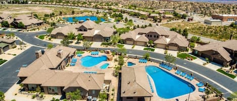 A residential area with multiple houses, a large swimming pool, and a clear view of mountains in the background.
