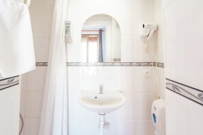 A bathroom with a white sink, a hand dryer, and a mirror. - Hostal Forum Tarragona (Tarragona)