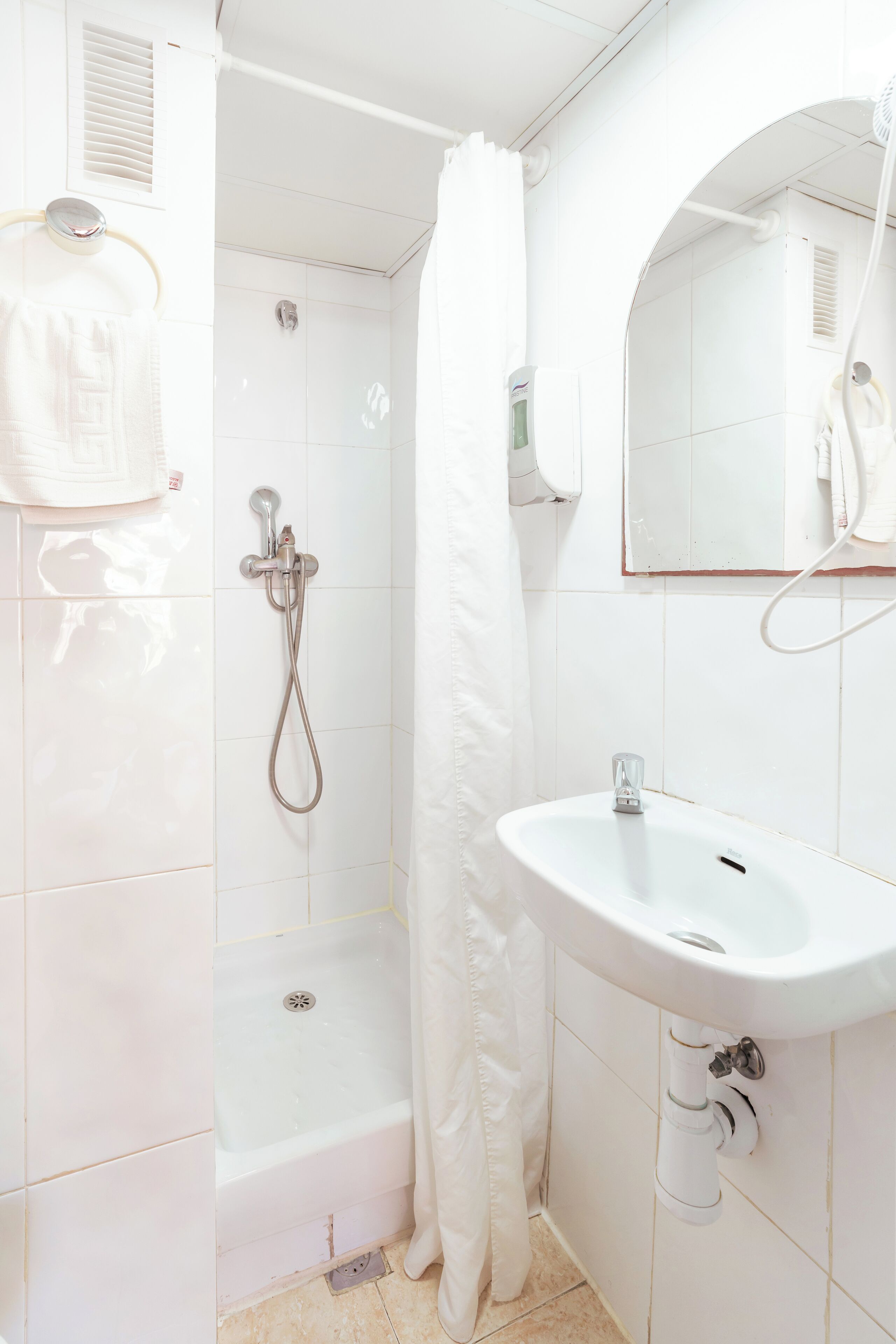 Un baño con un lavamanos blanco, una ducha y un espejo.