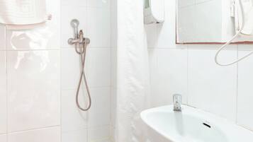 Un baño con un lavamanos blanco, una ducha y un espejo.