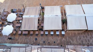 An outdoor terrace with multiple tables and chairs, umbrellas, and a brick wall. - Hostal Forum Tarragona (Tarragona)