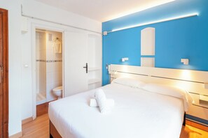 A hotel room with a bed, a bathroom, and a blue accent wall. - Hostal Forum Tarragona (Tarragona)