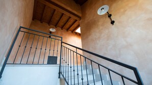 A staircase with a metal railing, wooden beams, and wall-mounted lighting fixtures. - Appartamento Victoria (Manerba del Garda)