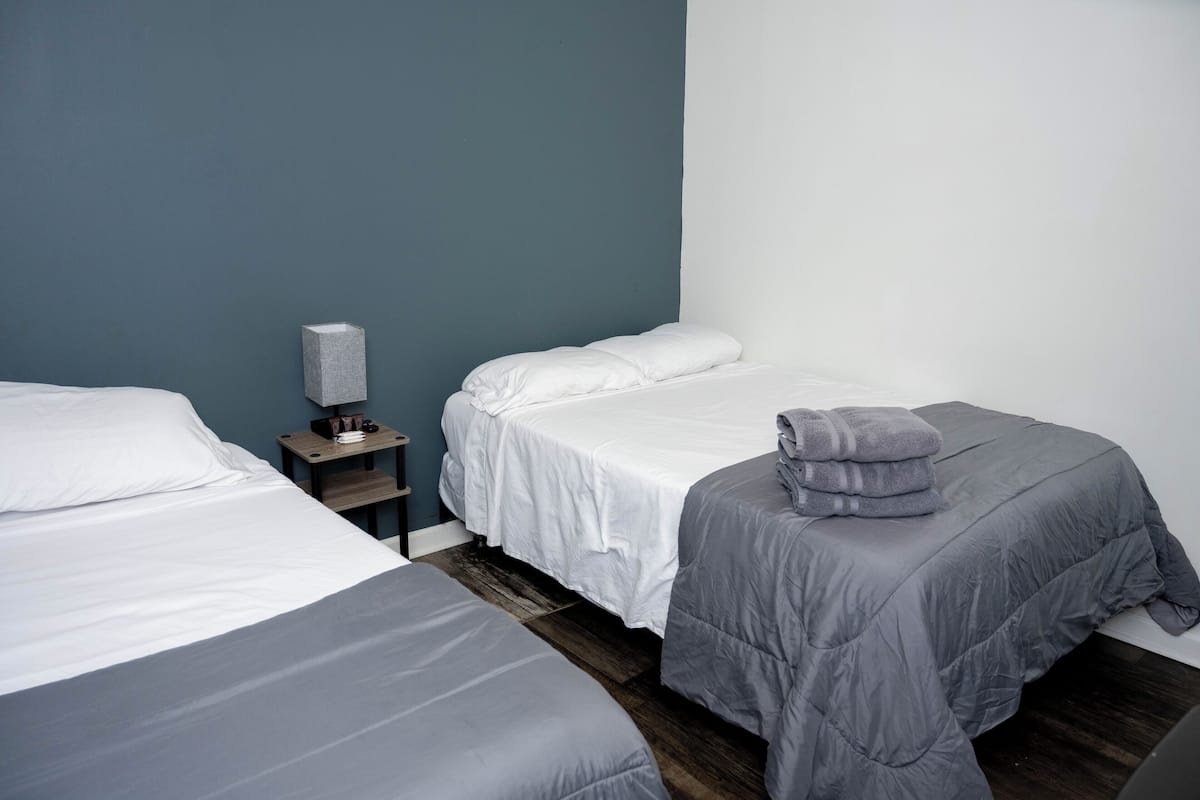 Una habitación de hotel con dos camas, una mesita de noche y un velador.