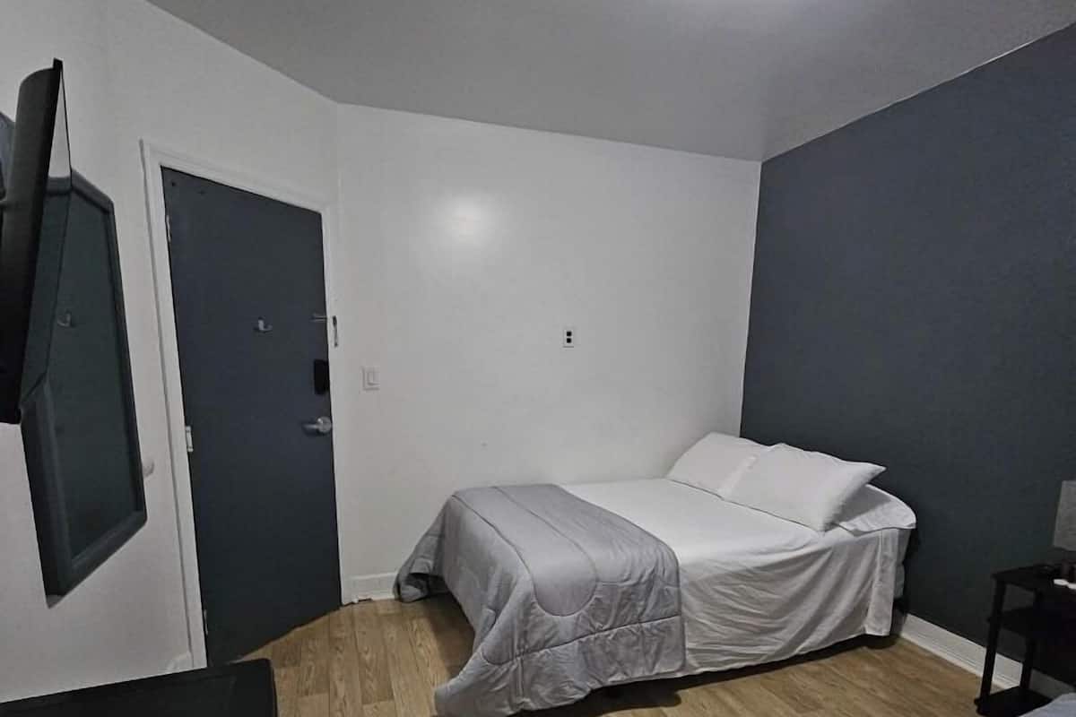 Un dormitorio pequeño y moderno con dos camas, un escritorio y una televisión montada en la pared.