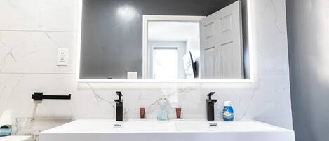 A bathroom with a white vanity, a large mirror, and a white toilet.
