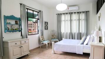 A bedroom with a bed, a dresser, a chair, a window with curtains, and an air conditioning unit.