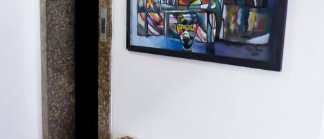 Un pasillo con suelo de baldosas, una puerta y un cuadro abstracto enmarcado en la pared.