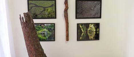 A room with a large tree trunk sculpture, a potted plant, and several framed pictures on the wall.