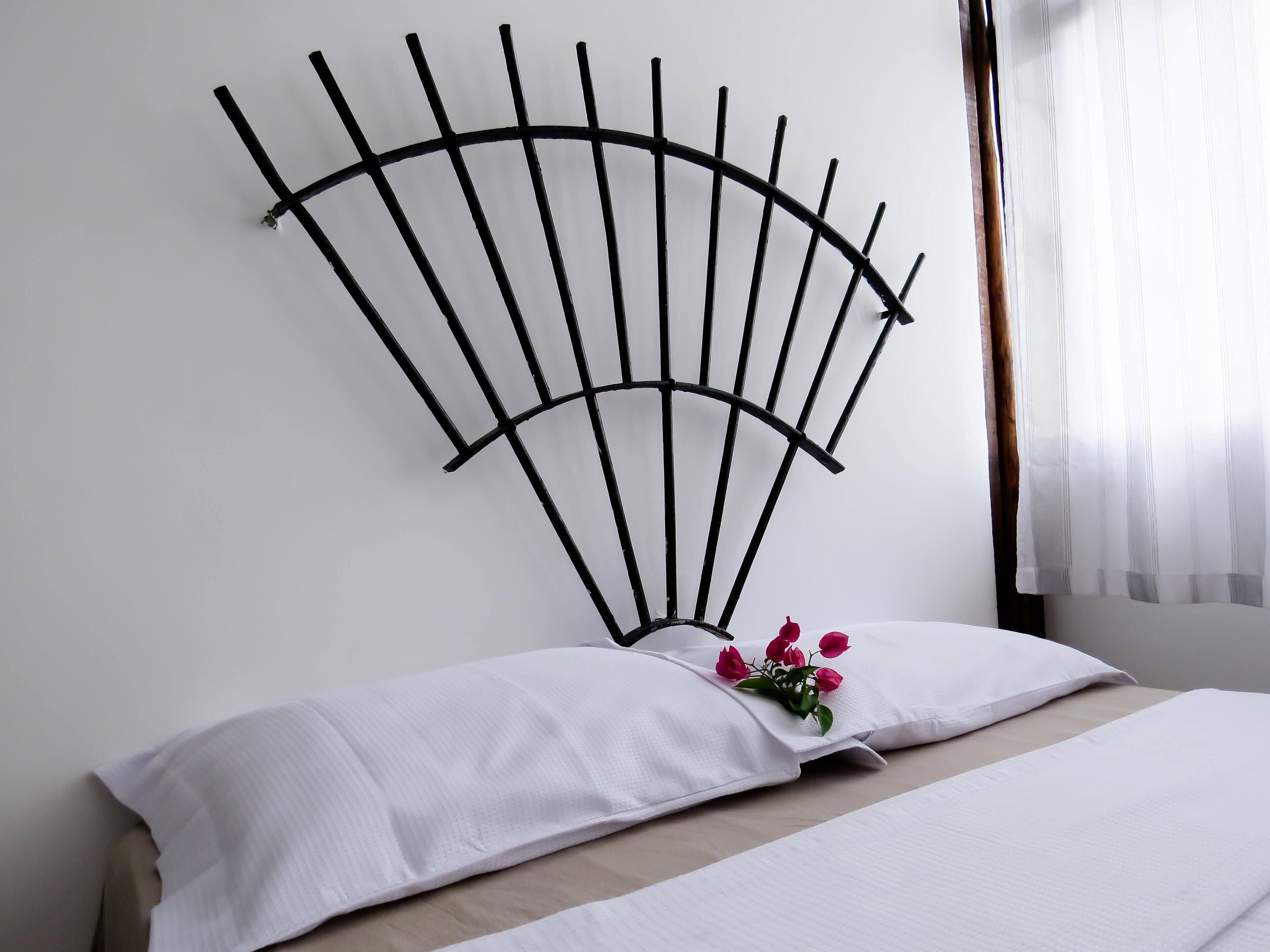 Een bed met witte lakens en een decoratief metalen hoofdeinde.