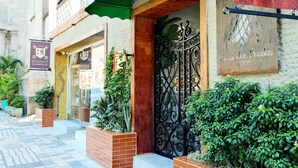 La entrada del Hotel Casa dos Frades, con un toldo verde, una reja de hierro forjado y plantas en macetas.
