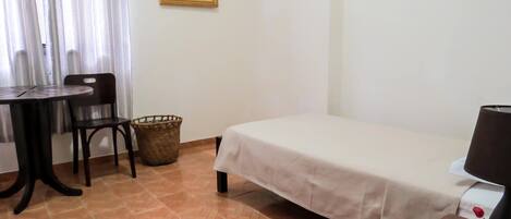 Una habitación con una cama, una mesa con sillas, un televisor y un cuadro en la pared.