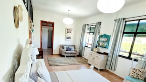 Un dormitorio con una cama grande, un aparador, un tocador y una ventana con cortinas.
