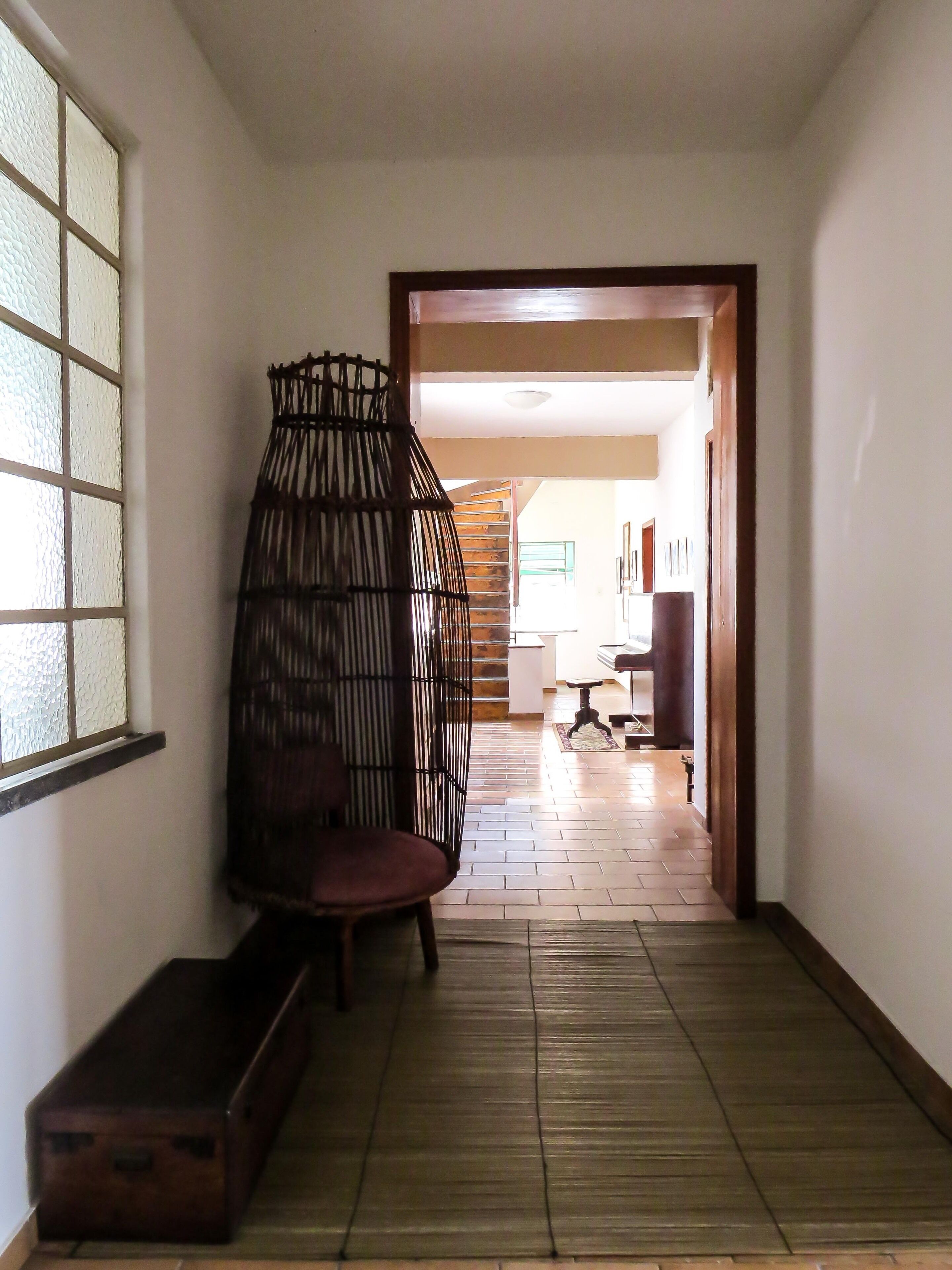 A hallway with a wooden bench, a wicker chair, and a wooden chest.