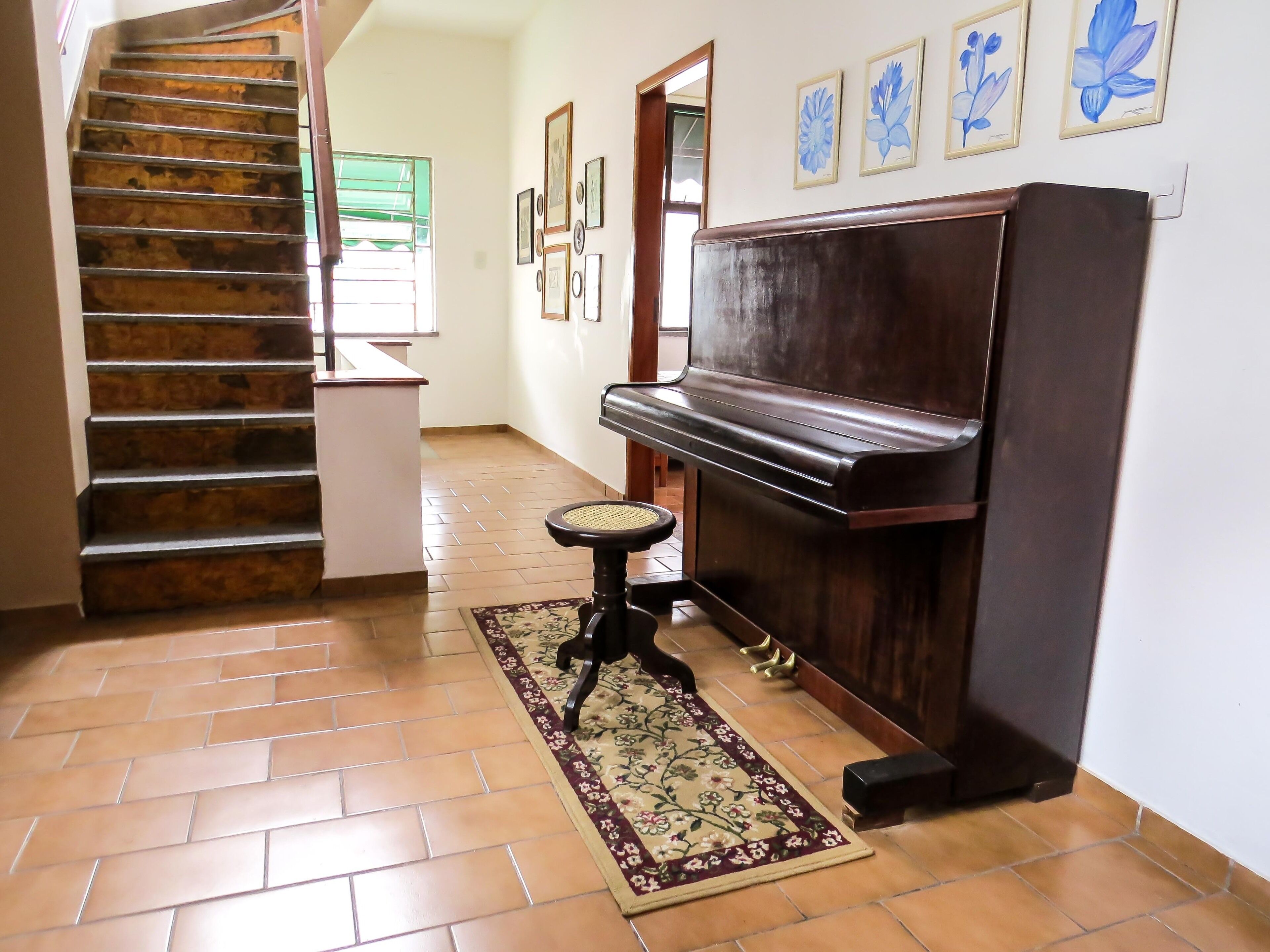 Un escalier avec des marches recouvertes de bois, un piano et un tapis à motifs dans un couloir.