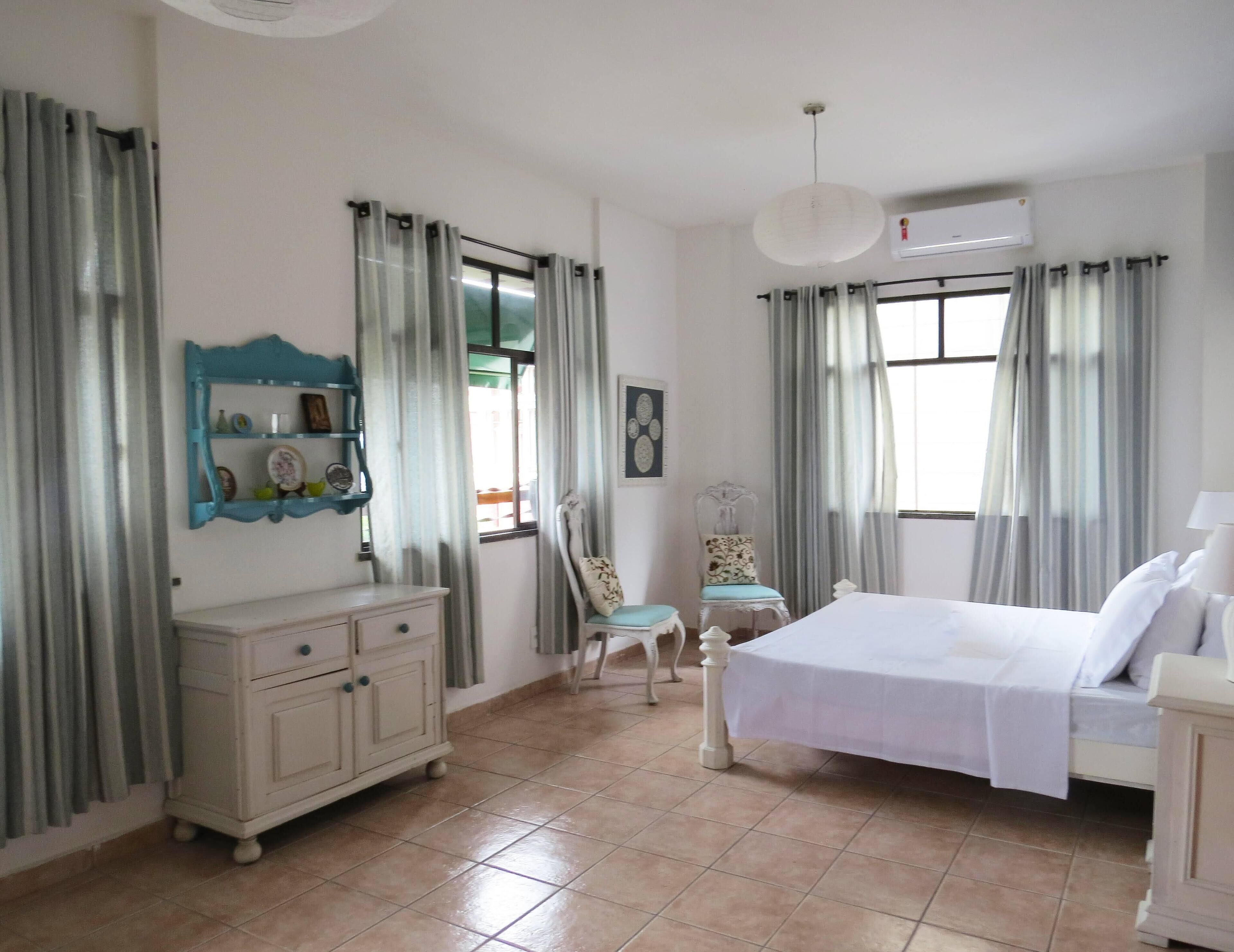 A bedroom with a bed, a dresser, a chair, and a window with curtains.