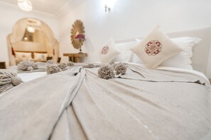 A neatly made bed with decorative pillows and a headboard. - Riad Janate & SPA - Suite Familiale (Marrakech)
