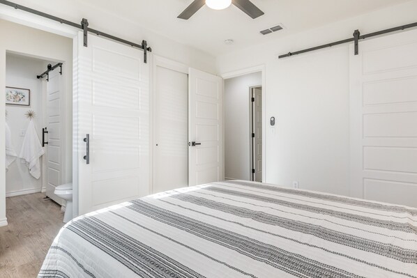 A bedroom with a bed, white doors, and a ceiling fan. - 18th Street Retreat (Dumas)