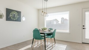 A dining area with a round table, green chairs, and a chandelier. - 18th Street Retreat  (Dumas)