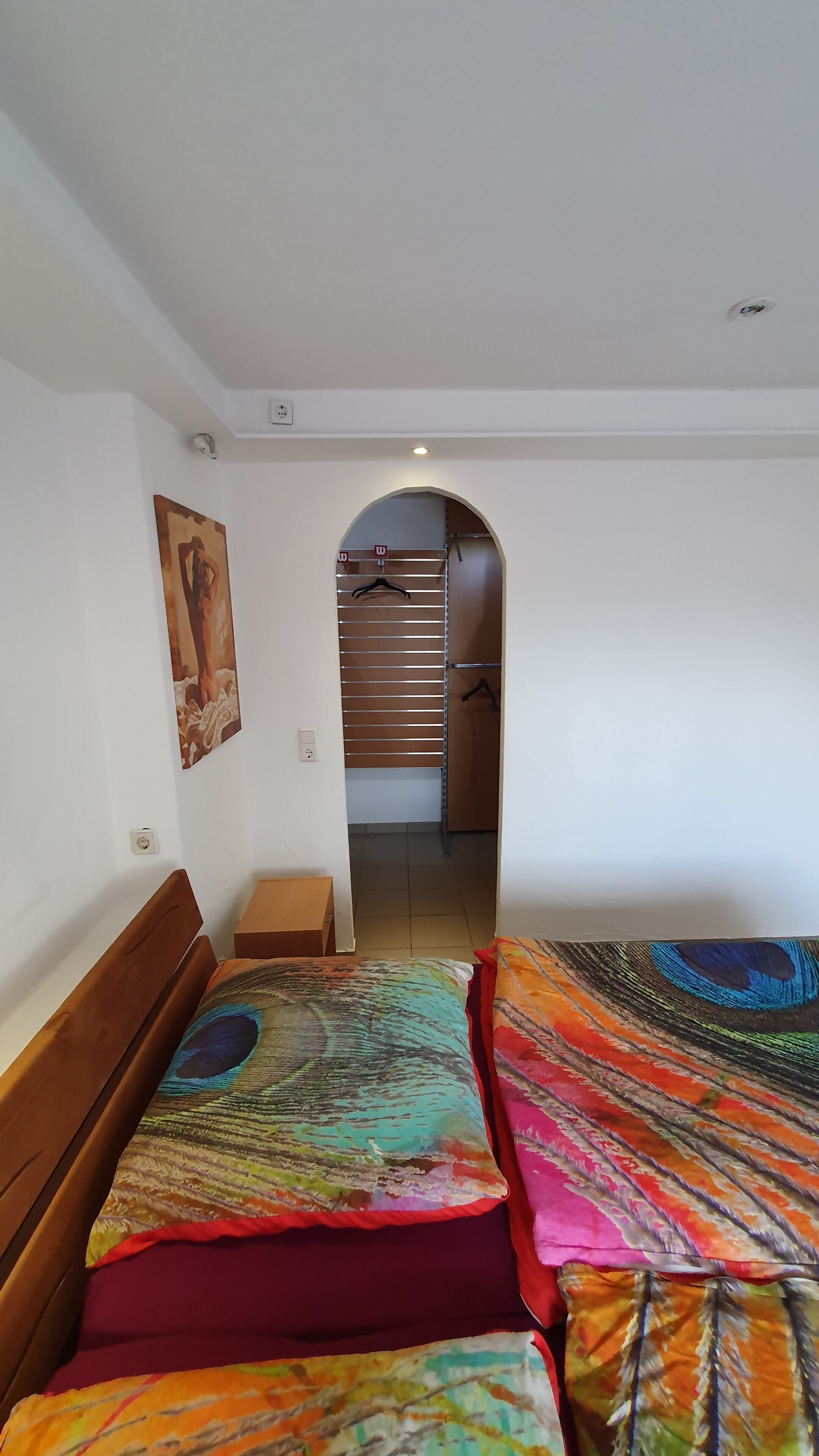 Ein Schlafzimmer mit zwei Betten, einem Kleiderschrank und einem Flur, der zu einem Badezimmer führt.