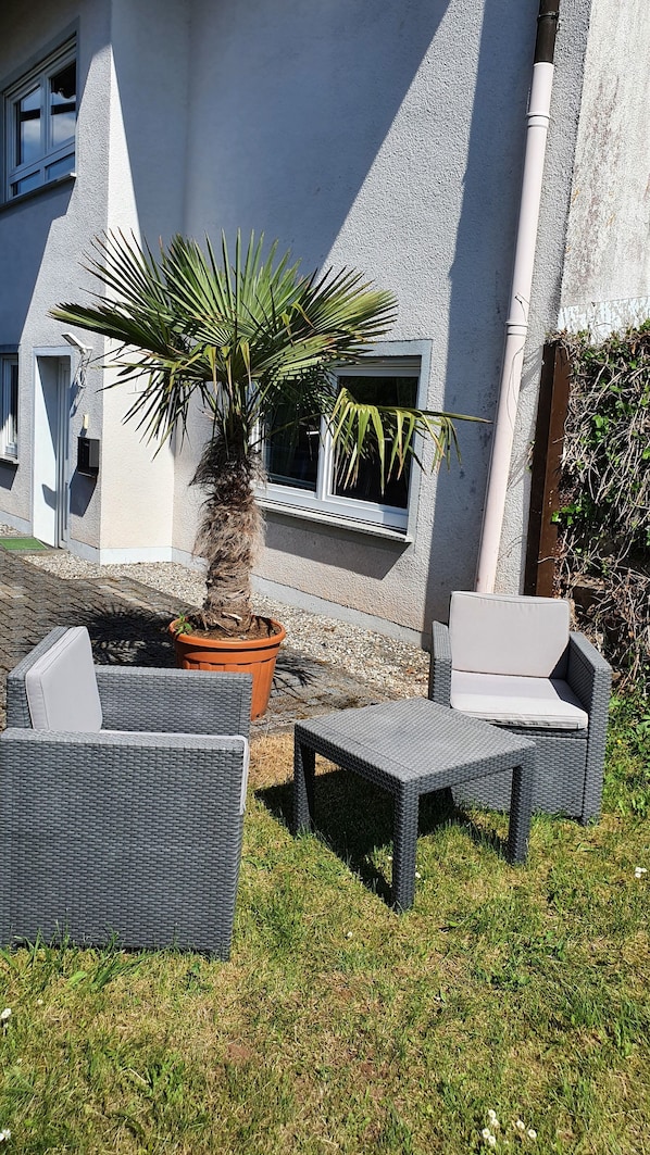 A patio area with outdoor furniture, a potted plant, and a building with windows and a door. - Moderne, Top Ausgestattete, Ruhige, Barrierefreie Ferienwohnung (Nonnweiler)