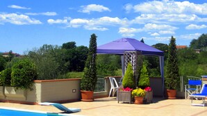 Un espace piscine aménagé sur le toit, avec une pergola, des chaises longues et des plantes en pot.