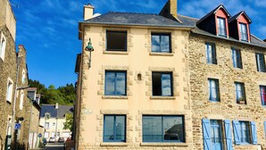 Un bâtiment en pierre de deux étages, doté de nombreuses fenêtres, d’une entrée bien visible et donnant sur la rue.