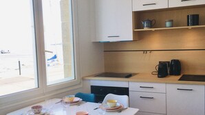 Une cuisine moderne avec des meubles blancs, une table à manger dressée avec des assiettes et des bols, et une machine à café posée sur le comptoir.