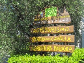 Un letrero de madera de varios niveles, cada uno mostrando textos diferentes relacionados con la agricultura y el turismo.