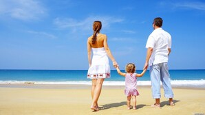 Una familia caminando sobre la playa bajo un cielo despejado.