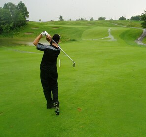 Una persona en un campo de golf preparándose para golpear una pelota.