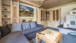 A cozy living room with a sectional sofa, a wooden coffee table, and built-in bookshelves. - Cosy apartment close to Kaprun and Kitzbühel (Stuhlfelden)