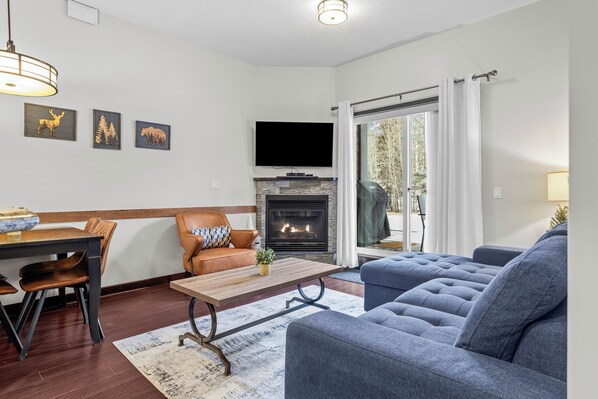A living room with a fireplace, a television, and a dining area with a table and chairs.