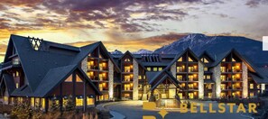 A multi-story hotel with a modern architectural design, featuring large windows and a stone facade.