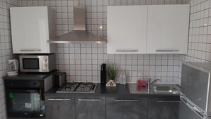 Una cocina moderna con estufa a gas, microondas, tostadora y electrodomésticos de acero inoxidable.