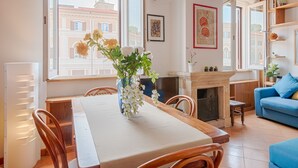A cozy living room with a dining table, chairs, a fireplace, and a blue sofa. - TREVI LUXURY PENTHOUSE with panoramic terrace (Roma)