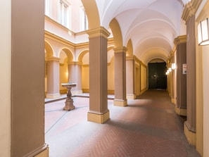 A corridor with arches, columns, and a fountain.