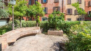 A courtyard with a brick archway, surrounded by greenery and buildings with multiple windows and shutters. - TREVI LUXURY PENTHOUSE with panoramic terrace (Roma)